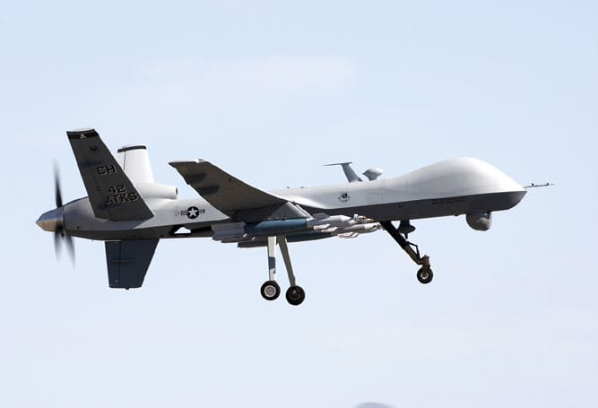 Eine Drohne vom Typ „Reaper“ fliegt am Himmel. Unten sind Raketen erkennbar.