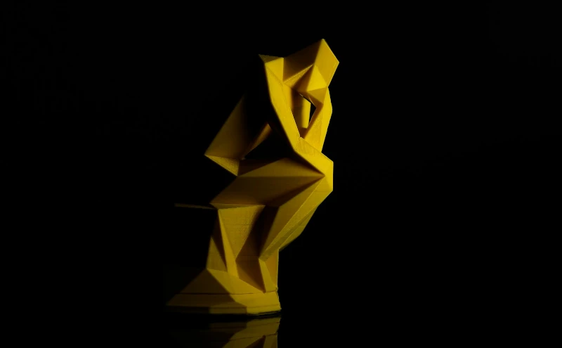 Eine Figur in Denkerpose auf schwarzem Hintergrund – 3D-gedruckt aus gelbem Filament.